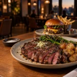 Grilled ribeye and cheeseburger on a warmly lit restaurant table